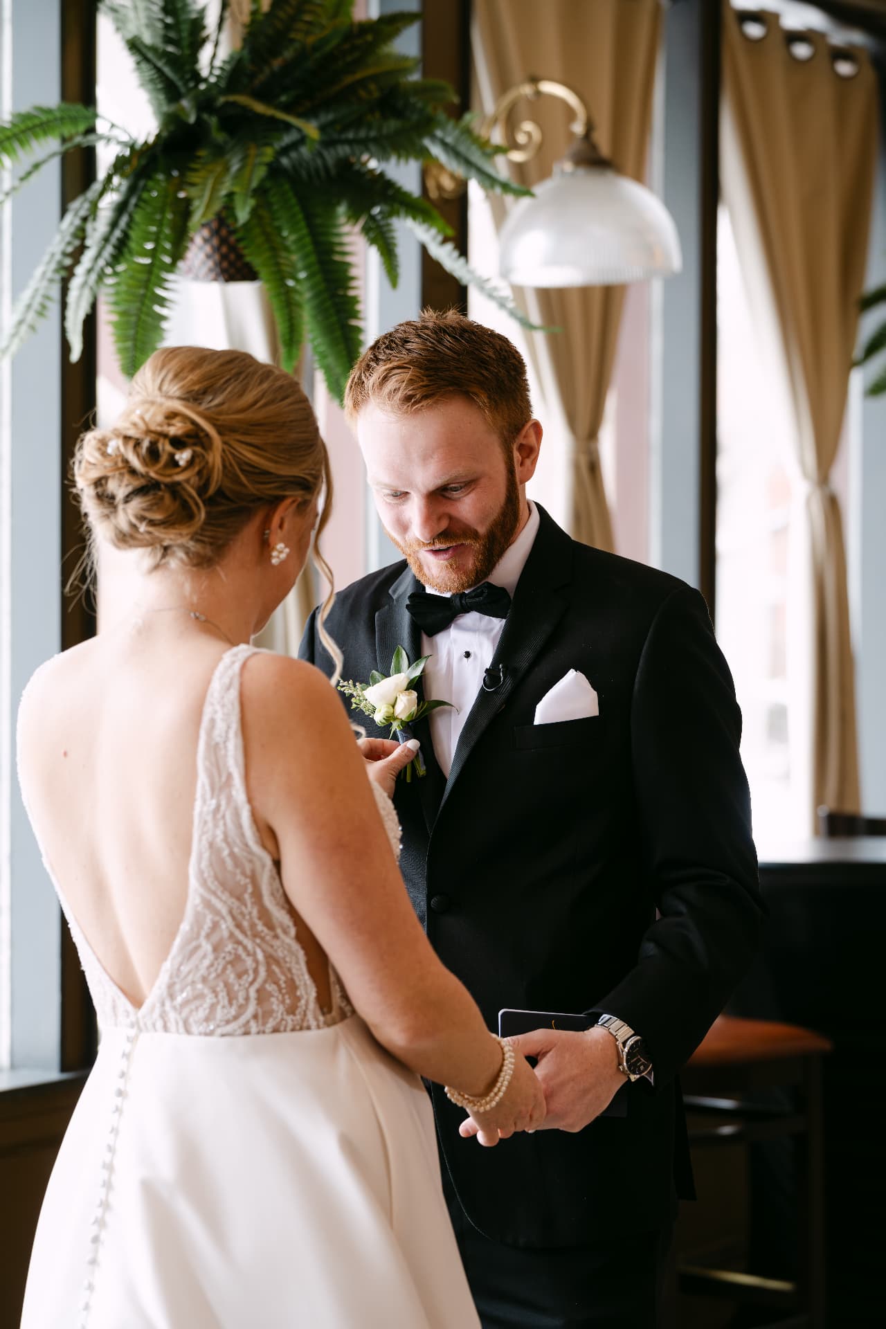 One partner pinning the boutonniere on the other during a first look
