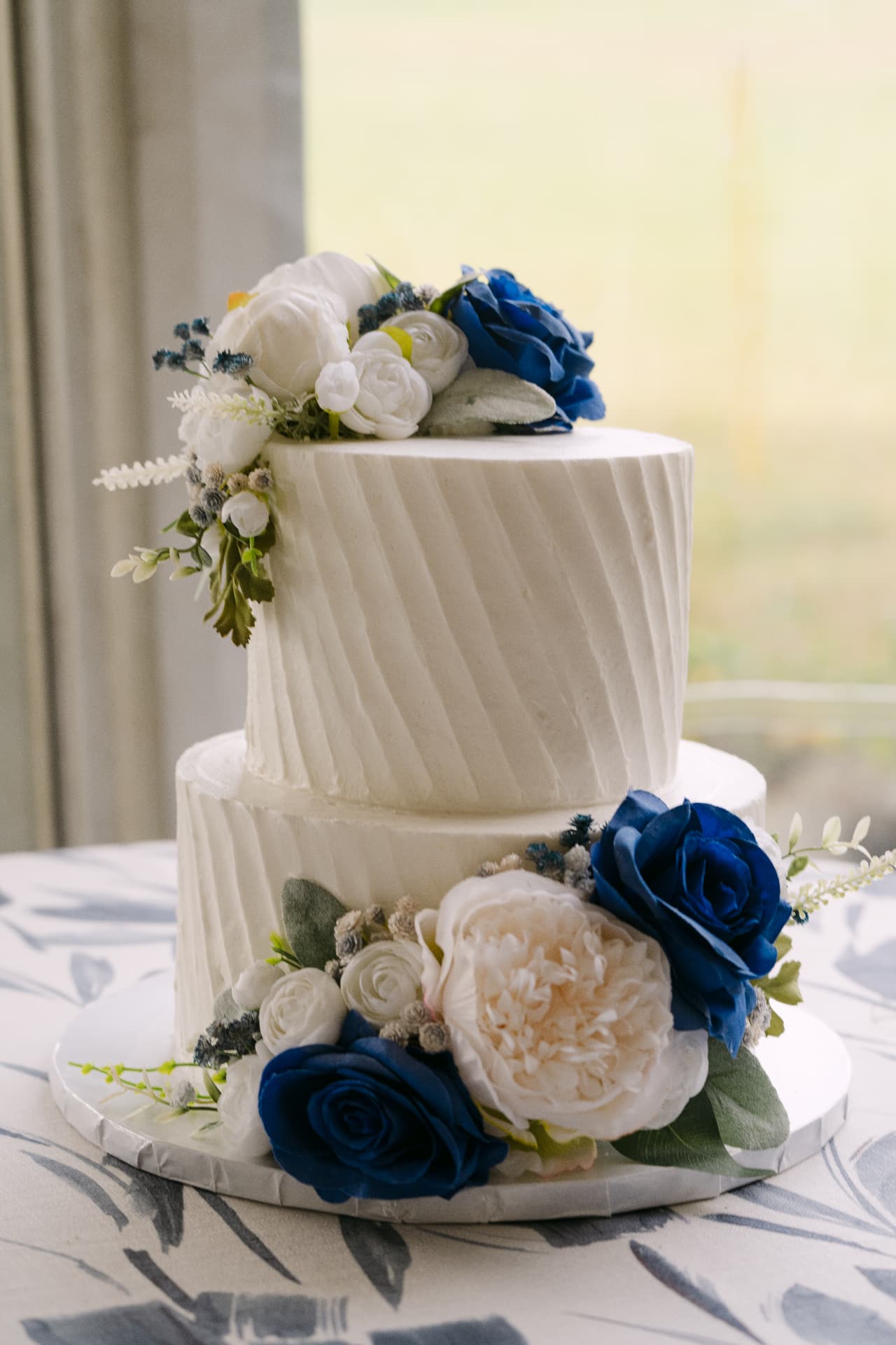 Two tier white wedding cake with blue and ivory roses