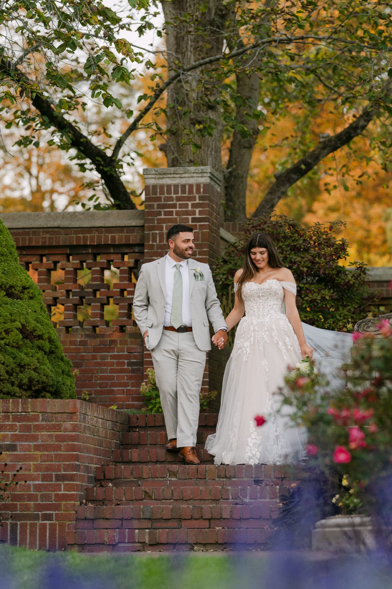 Couple walking hand in hand down brick garden steps in autumn