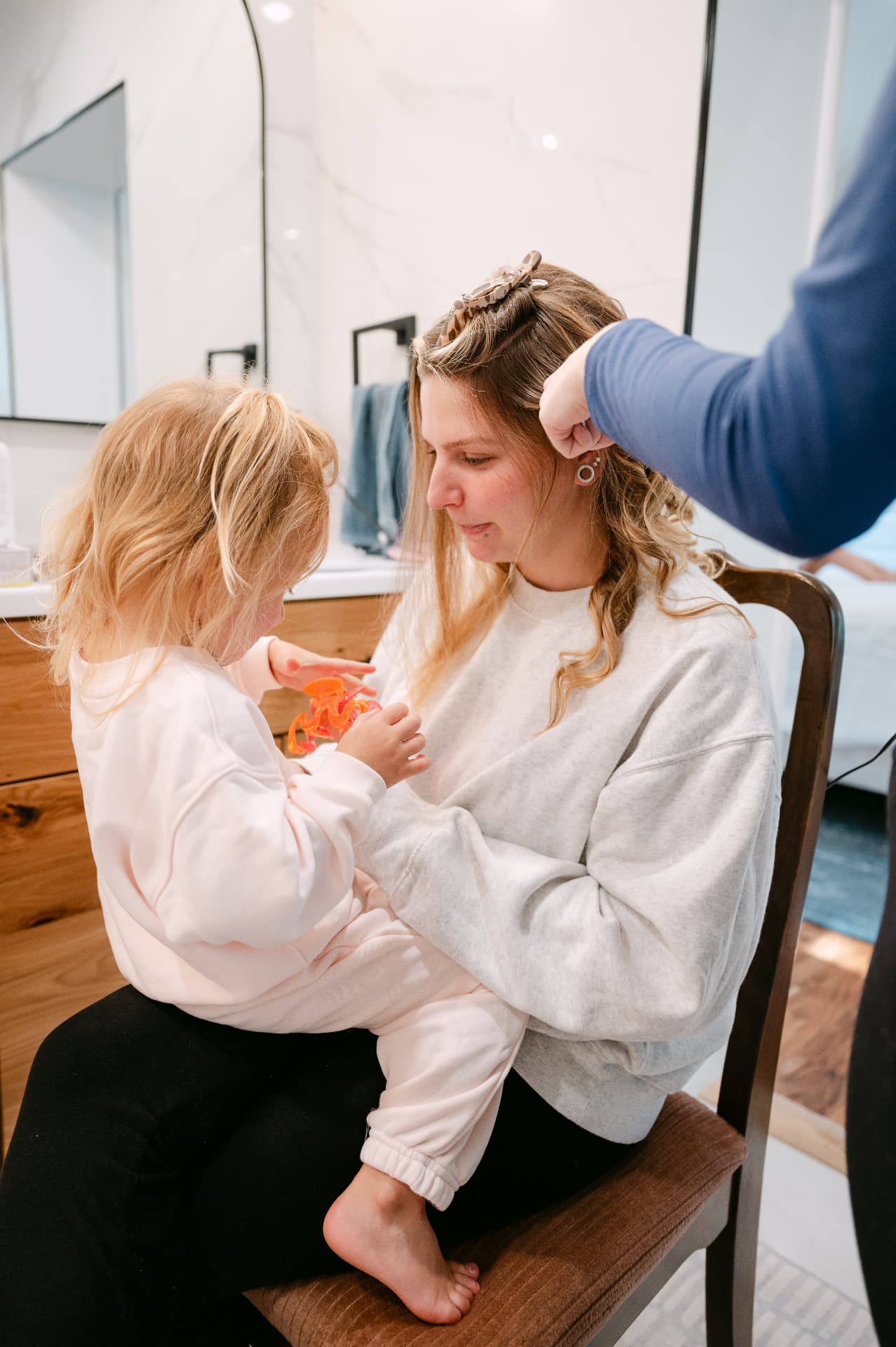 A parent holding their child while their hair is styled during morning prep