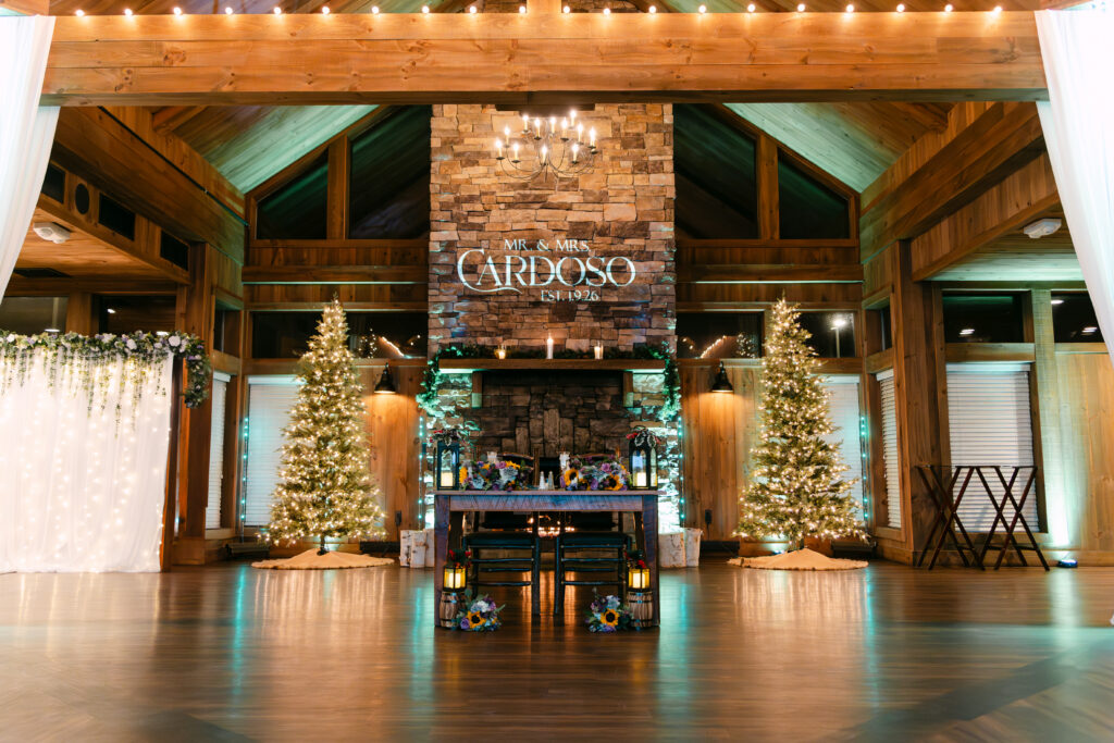 Reception space set up for winter wedding at Birch Wood Vineyards in Derry New Hampshire with Christmas trees and warm lighting