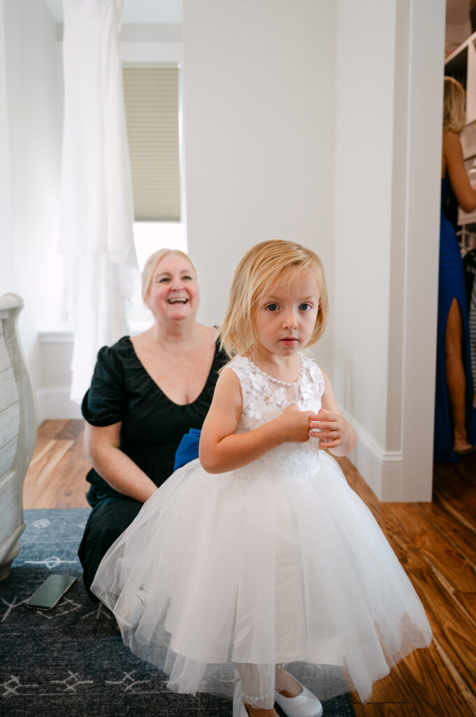 Massachusetts Wedding Planner helps flower girl get ready during wedding Photographed by A Massachusetts Wedding Photographer