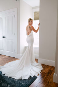  Bride standing by natural window light in fitted wedding dress before ceremony Massachusetts wedding planner and photographed by Massachusetts wedding photographer